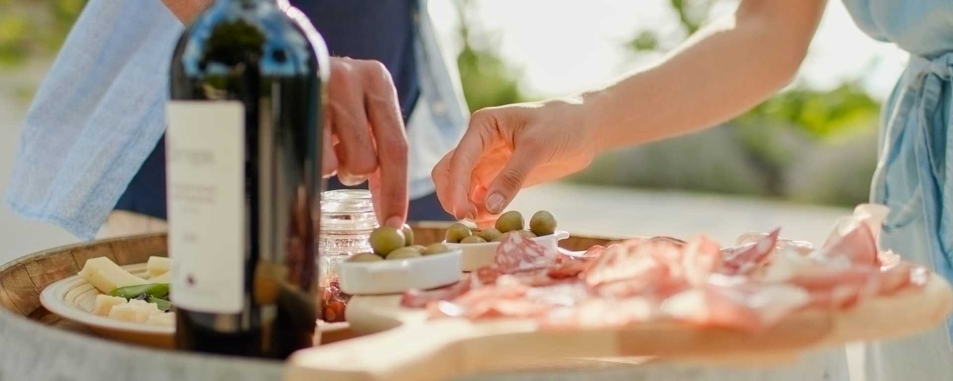 Couple tasting a selection of olives, cured meats, cheeses and wine at a vineyard in Umbria, Italy