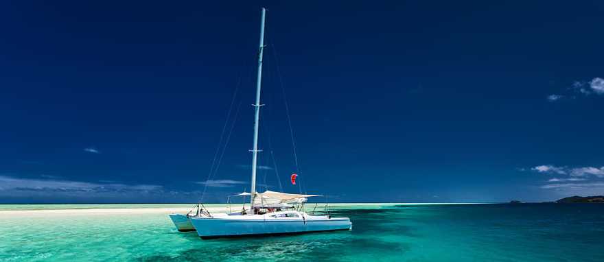 White catamaran on tropical island in Fiji White catamaran on tropical island in Fiji