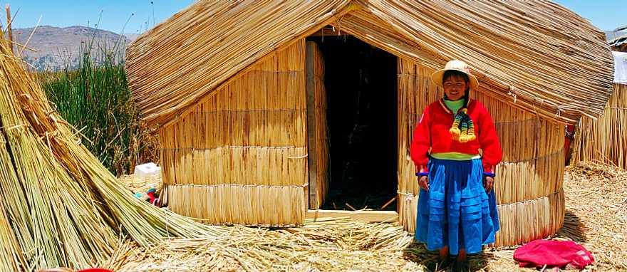 A girl standing on a floating Uros island standing in front of her home in Lake Titicaca, Peru. A girl standing on a floating Uros island standing in front of her home in Lake Titicaca, Peru.