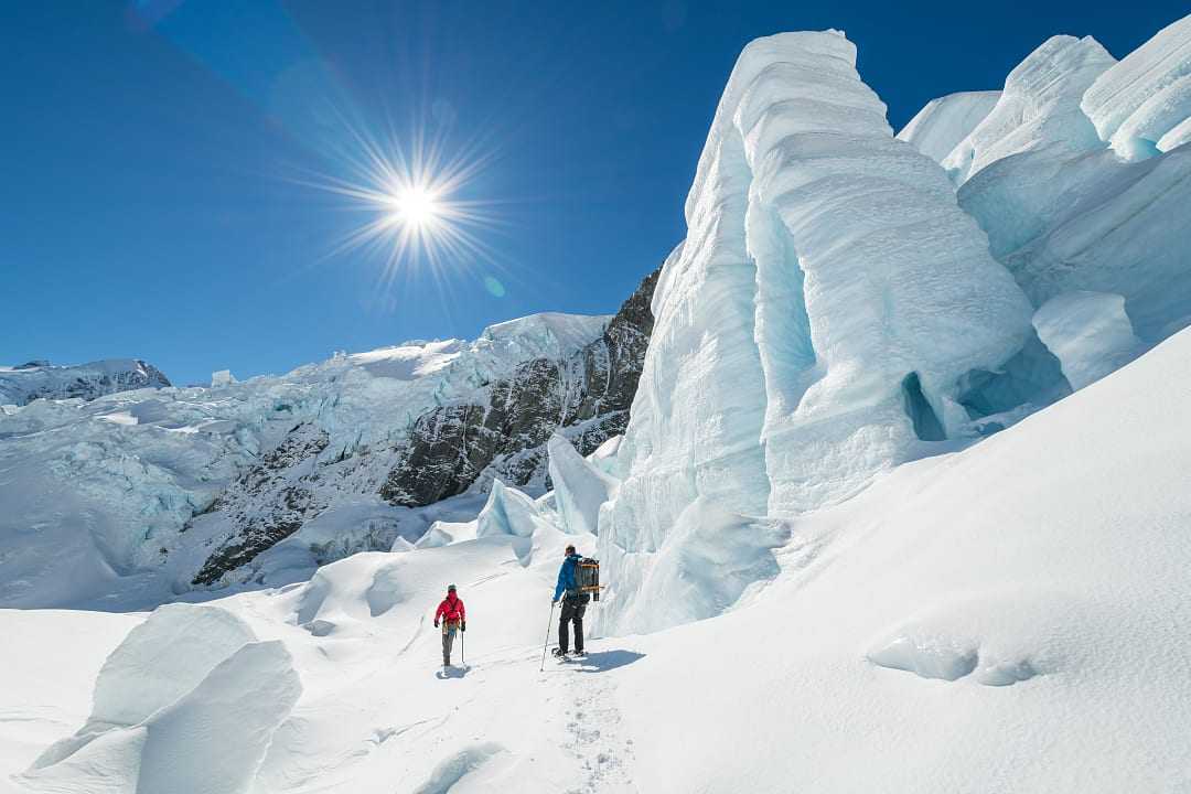 Two people hiking Tasman Glacier in Mount Cook National Park, New Zealand