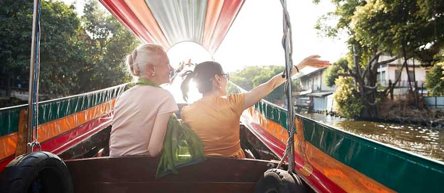 Bangkok, Thailand Senior travelers riding a colorful longtail boat through a canal at sunset in Bangkok, Thailand