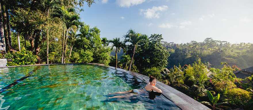 Woman lounging in an infinity pool at a luxury resort in Bali, Indonesia Woman lounging in an infinity pool at a luxury resort in Bali, Indonesia