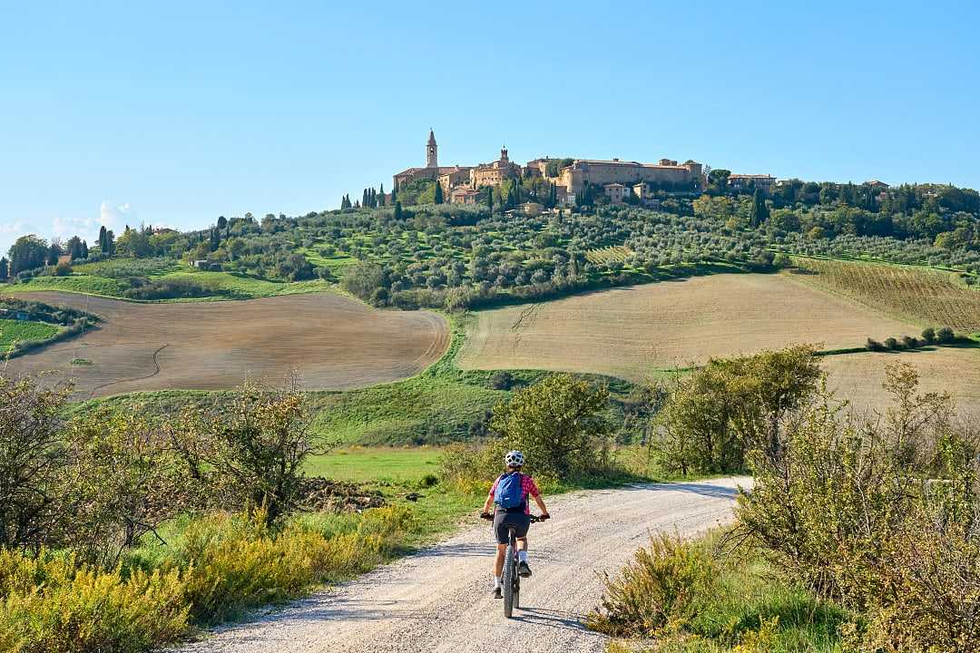 Woman biking on dirt road towards Pienza in Tuscany, Italy