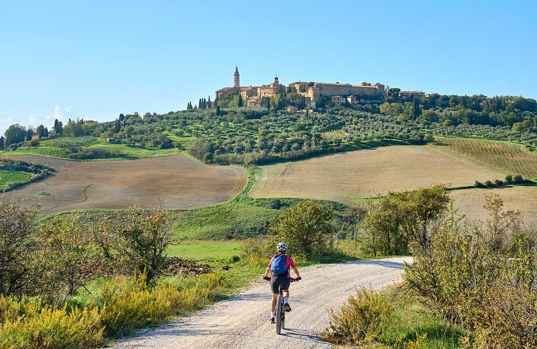 Pienza in Tuscany, Italy Woman biking on dirt road towards Pienza in Tuscany, Italy