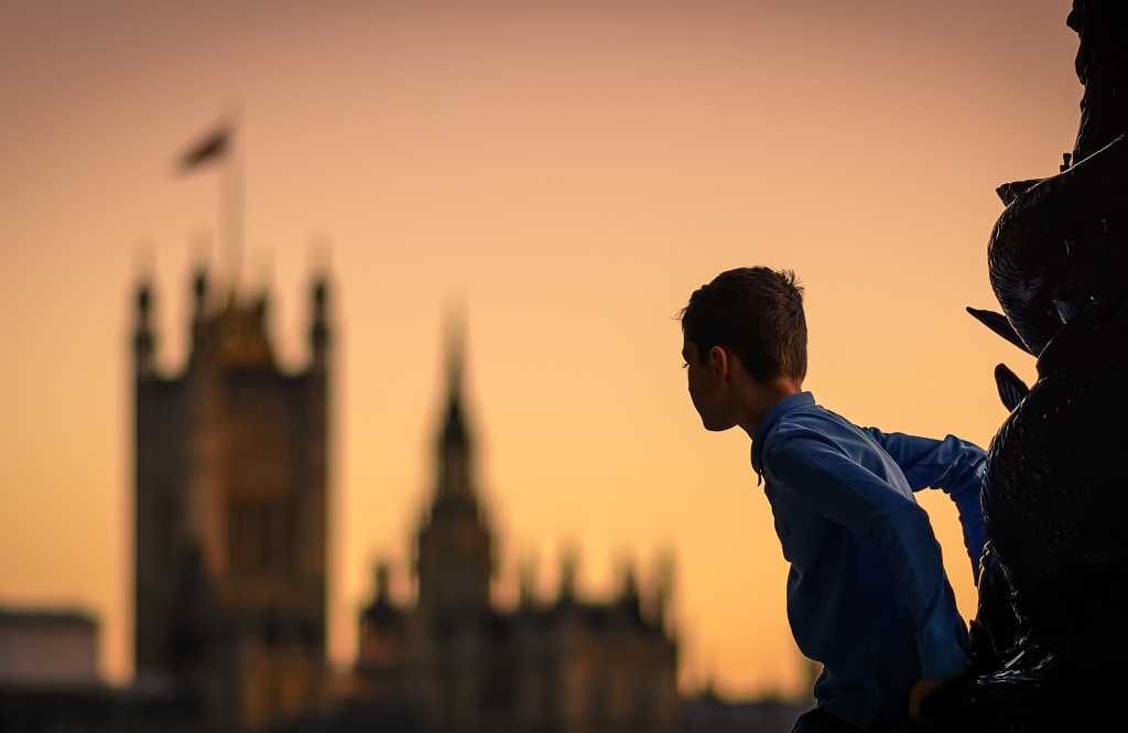 Child in London, England Child climbing a lamp post in south bank in london (uk) at sunset with the houses of parliament in the background