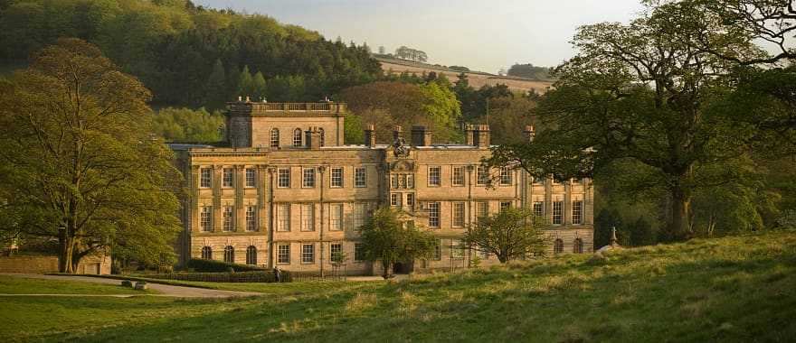 Elegant historic manor house in the English countryside, surrounded by lush greenery and rolling hills