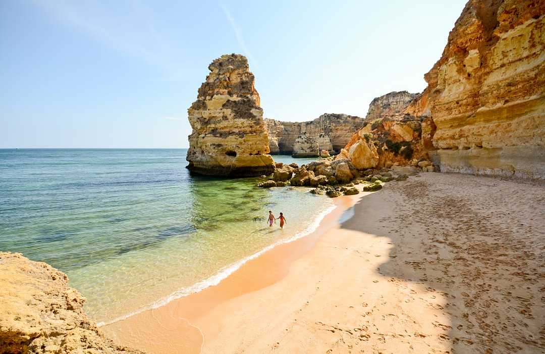 Praia da Marinha in Lagos, Portugal Couple in the water surrounded by limestone cliffs at Praia da Marinha in the Algarve